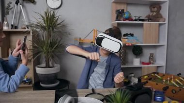Video oyunları oynarken video kulaklık ve cep telefonu kullanarak eğlenen iki gencin komik bir fotoğrafı.