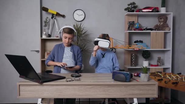 Закрыть обзор улыбающимся красивым мальчикам 10-12 лет, которые наслаждаются видеоиграми с помощью специальных виртуальных 3D очков и планшетного компьютера — стоковое видео