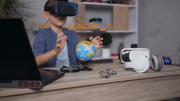 Appel adolescent sérieux moderne portant casque de réalité virtuelle et téléphone clouant la structure du globe — Video