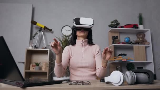 Krásná koncentrovaná moderní žena používající sluchátka virtuální reality dotýkající se čehosi ve vzduchu doma — Stock video