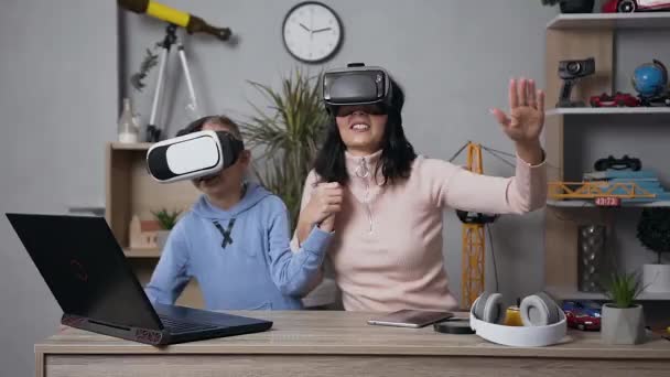 漂亮的黑头发年轻女人和她那笑着的儿子玩电子游戏用的是保护虚拟3D眼镜 — 图库视频影像