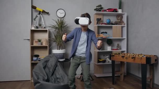 Front view of funny smiling teen boy which using virtual reality headset jumping while enjoying in video game — Stock Video