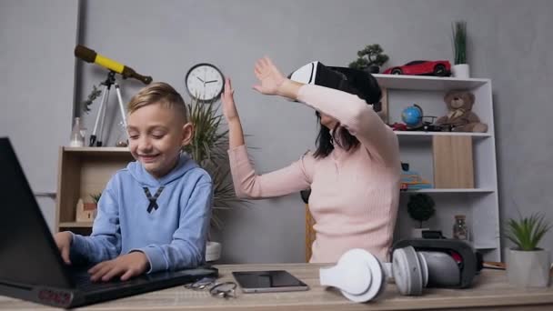 Mulher morena bonita no vr e seu filho sorridente de 10 anos usando o computador em casa — Vídeo de Stock