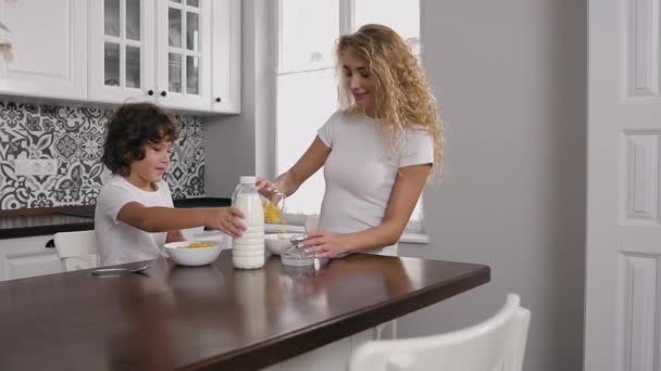 Mujer joven desayunando con su hijo en casa en la cocina moderna — Vídeos de Stock