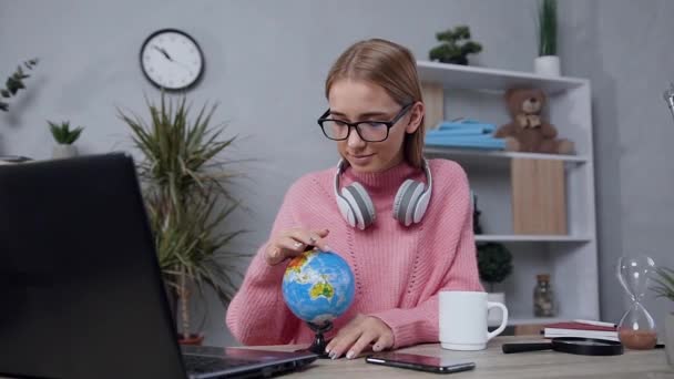 Beautiful satisfied trendy blond woman in glasses spinning the small globe and choosing the country where she dreams to travel — Stock Video