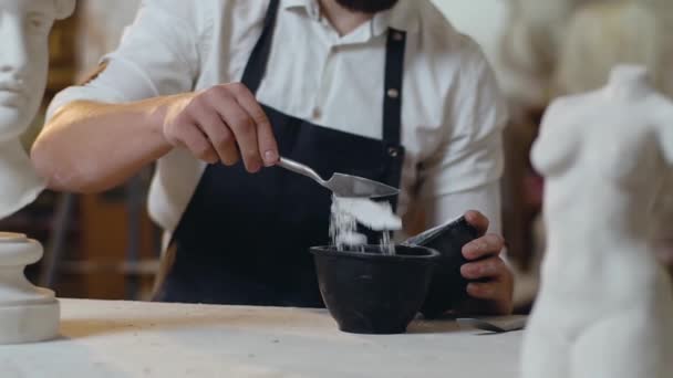 不知名的胡子男雕塑家，在碗中加入特殊的干物质，准备用于雕塑品的胶水 — 图库视频影像