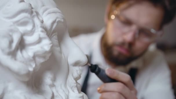 Affascinante creativo 30-aged moderno maestro maschio con barba che lavora con strumento di lucidatura e sculture fatte a mano testa in occhiali speciali — Video Stock