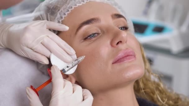 Cosmetologo professionista in guanti che fanno le iniezioni facciali ringiovanenti per levigare rughe sulla pelle di faccia femminile — Video Stock