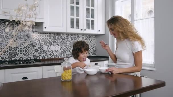 若いですお母さんとともに5-age子供食べる健康的な朝食でザホームキッチン — ストック動画