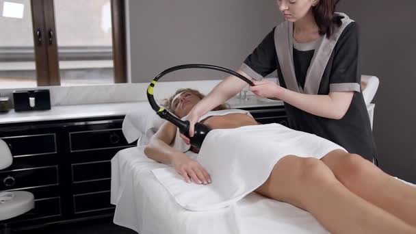 Slow motion van aantrekkelijke vrouwelijke schoonheidsspecialiste die doet rf-lifting massage op vrouwen maag in spa salon — Stockvideo