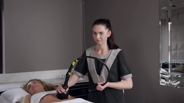 Sonriente masajista profesional haciendo rf-lifting procedimiento en las mujeres del estómago y posando en la cámara — Vídeos de Stock