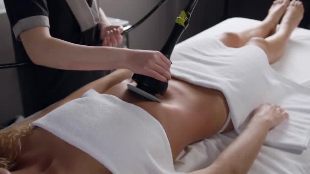 Onbekende ervaren cosmetoloog die speciale massage-instrument doen anti-cellulitis procedure op vrouwen buik — Stockvideo