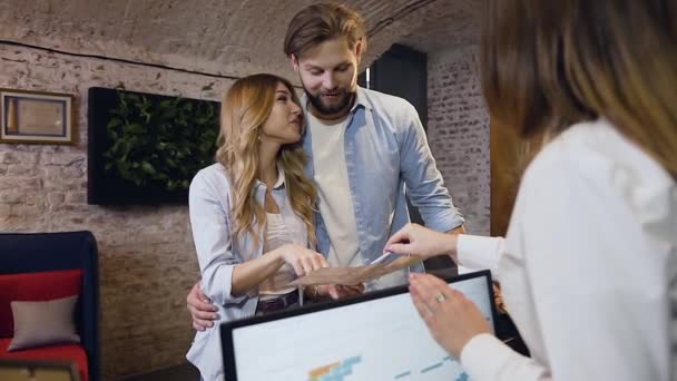 Unrecognizable female receptionist showing interesting places on map to the attractive young happy couple at the reception desk — Stock Video