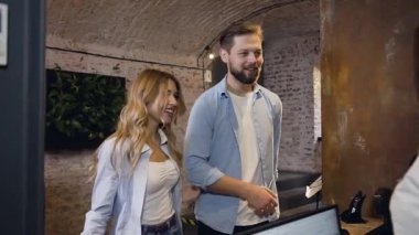 Good-looking hospitable modern couple giving their passports for registration to the fiendly female manager at the check-in desk