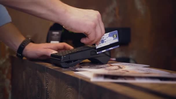 Aantrekkelijke mannelijke hand in het bezit van plastic creditcard betalen voor verblijf in het hotel — Stockvideo