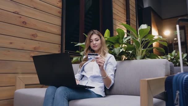 Zijaanzicht van elegante zelfverzekerde moderne blondine die online bankieren met behulp van haar creditcard en laptop — Stockvideo