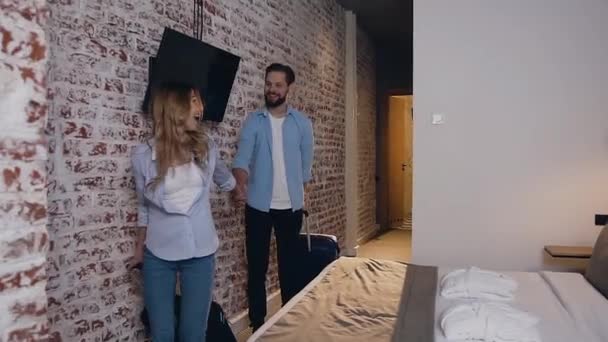 Χαμογελώντας όμορφο νεαρό ζευγάρι εισέρχεται στο δωμάτιό τους στο σύγχρονο ξενοδοχείο και είναι πολύ έκπληκτος από δει — Αρχείο Βίντεο