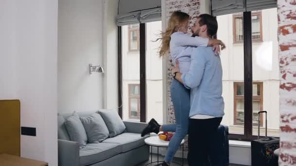 Romántico feliz pareja joven y moderna abrazando, dando vueltas y divirtiéndose juntos en la habitación de hotel — Vídeo de stock