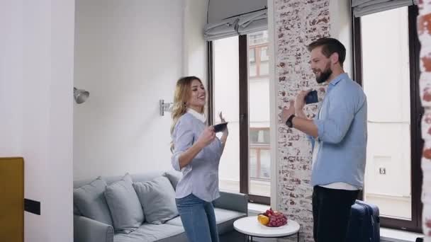 Attractive portrait of high-spirited cheerful modern guy and girl which funny dancing with their passports in hotel room — Stock Video