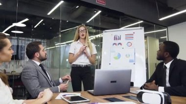 Likable confident modern businesswoman explaining the business strategy of joint work for the high-skilled multiethnic serious business people