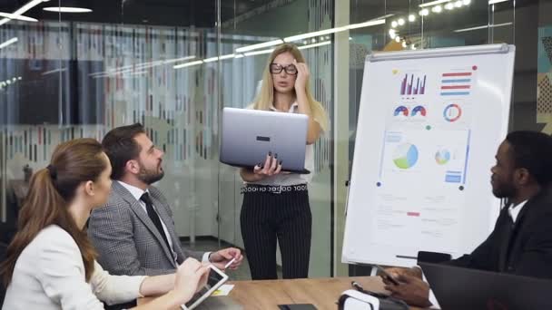 Zakelijk concept waar aantrekkelijke blonde zakenvrouw presenteren zakelijke strategie met behulp van flip-over bord voor de diverse goed uitziende vertrouwen zakelijke mensen — Stockvideo