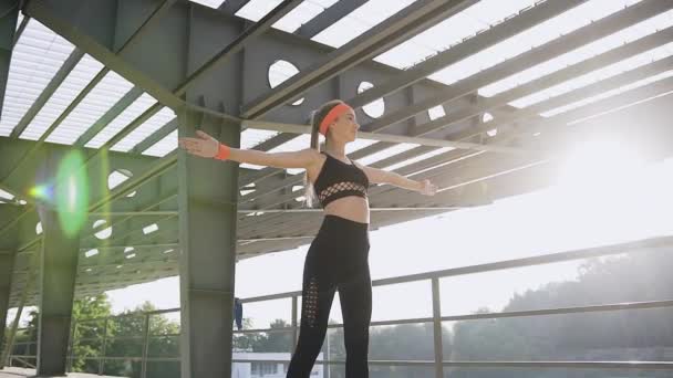 Beautiful athletic slim young girl doing fitness hand exercises on special sportground on the stadium on sunny day — Stock Video