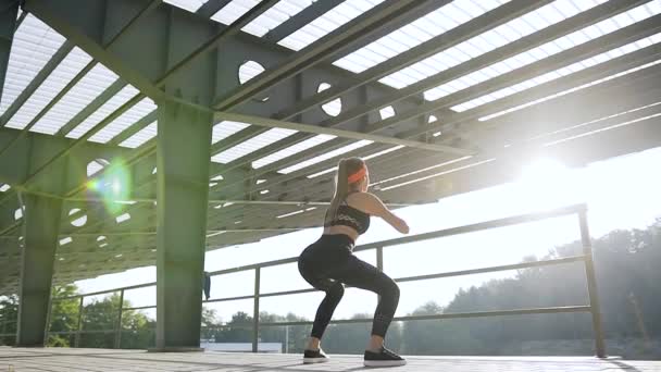 Concepto de fitness donde hermosa mujer joven deportiva delgada en ropa deportiva haciendo ejercicios en cuclillas en el suelo al aire libre — Vídeos de Stock