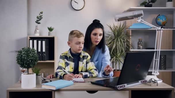 Front view of appealing dark hair 35-aged woman which working together with her handsome little boy at the computer — Stock Video