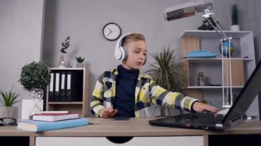 Attractive amusing teenage boy in earphones dancing under modern songs in his room