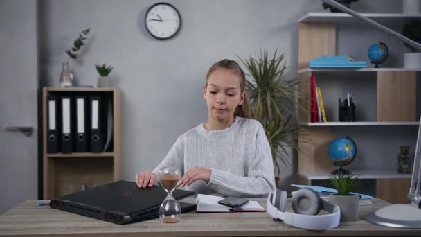 Atraktivní blondýny teen dívka v pleteném svetru poslech hudby ve sluchátkách po její práci na počítači — Stock video