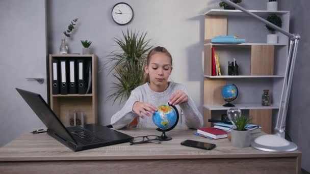 Vista frontal de la chica adolescente inteligente y moderna que explora el pequeño globo con lupa en su habitación — Vídeos de Stock