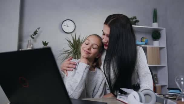 Schöne glücklich lächelnde Mutter und ihre jugendliche Tochter sitzen zusammen am Tisch und sehen Videos auf dem Computer — Stockvideo
