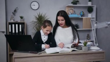 Eğitim konsepti, okul üniformalı gülümseyen genç bir kızın güzel esmer annesiyle hometask yaptığı yer.
