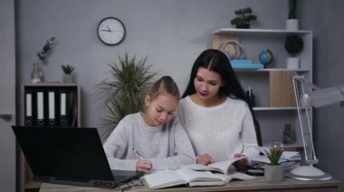 Slow motion of good-looking confident brunette woman which learning lessons with her pretty light hair teen daughter