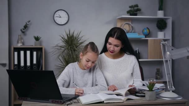 Powolny ruch przystojny pewny siebie brunetka kobieta, która uczy się lekcji z jej dość lekkie włosy nastolatka córka — Wideo stockowe