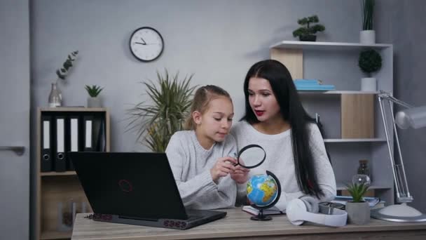 Vista anteriore di attraente grave bruna donna di 35 anni che aiuta a fare geografia hometask insieme a sua figlia adolescente — Video Stock