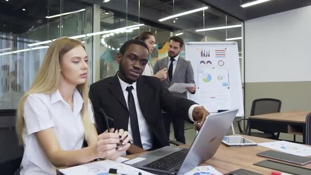 Front view of purposeful professional mixed race business people which working on computer during joint project while another their colleagues discussing the datas of charts standing away — 图库视频影像