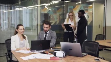 Slow motion of multiracial considerate young business colleagues which working under joint project in the meeting room using laptop and different reports