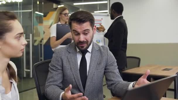 Front view of professional enterprising bearded businessman which emotionally telling to his considerate female colleague about opportunities about better results of their joint project on the — Stockvideo