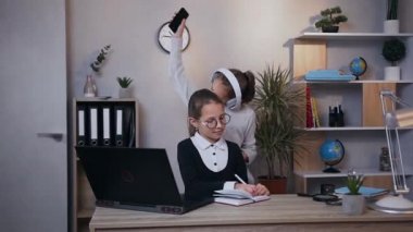 Kulaklıklı komik, genç bir kızın ön görüntüsü. İltihaplı müzik eşliğinde dans ederken bir başka gülümseyen kız da deftere notlar yazıyor.