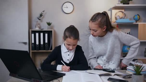 Elégedett tinédzser idősebb lány ad pacsit a húgának, miközben otthon együtt csinálják a házi feladatot. — Stock videók