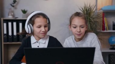 Çocuk odasında oyun oynarken dizüstü bilgisayarın önünde birlikte eğlenen güzel kızlar.