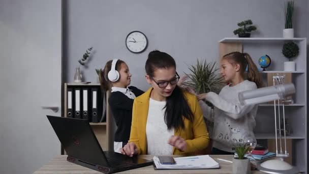 Serio confiado morena mujer de negocios en gafas peleando sus ruidosas hijas adolescentes que interfieren para trabajar con el informe — Vídeos de Stock