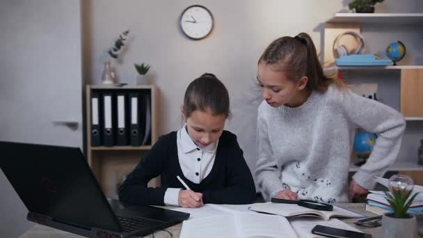 Tevreden tiener ouder meisje geven high five naar haar jongere zus terwijl samen hometask thuis — Stockvideo