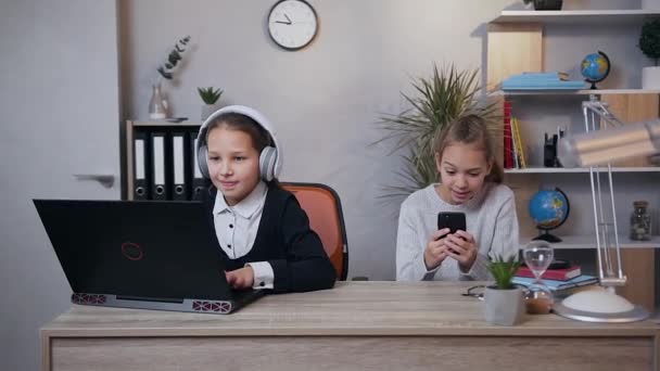 Bela emocionante adolescente meninas jogando videogame no laptop e telefone simultaneamente e celebrando a vitória — Vídeo de Stock