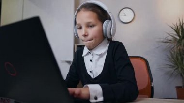 Slow motion of beautiful happy teen girl in headphones which playing video game on computer and raised her hands up after victory