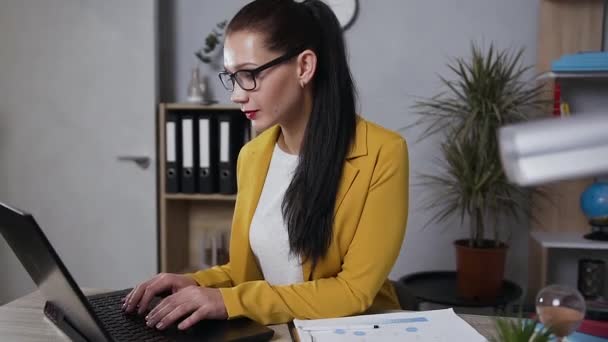 Zeitlupe von attraktiven ernsthaften erwachsenen brünetten Geschäftsfrau in trendigen Jacke, die im Homeoffice am Computer arbeitet — Stockvideo