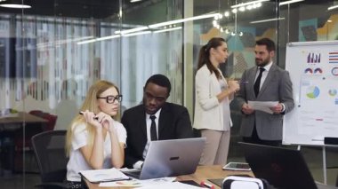 Close up of good-looking satisfied high-skilled male and female business people which working under joint project in boardroom