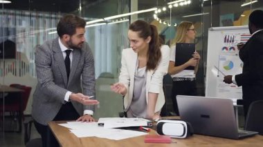 Satisfied industrious modern multiracial corporate coworkers consulting about the details of their joint project in meeting room