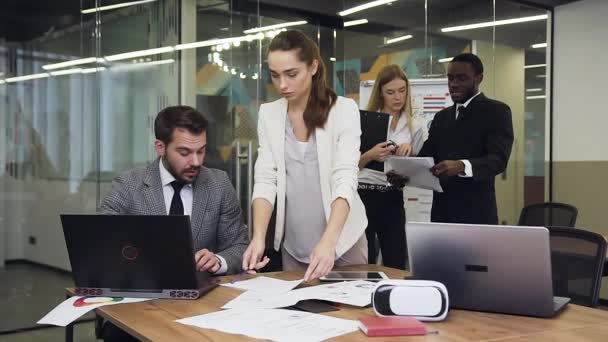Бизнес-концепция, где симпатичный опытный бородатый бизнесмен подписывает документы в зале заседаний, в то время как его деловые партнеры обсуждают проект — стоковое видео